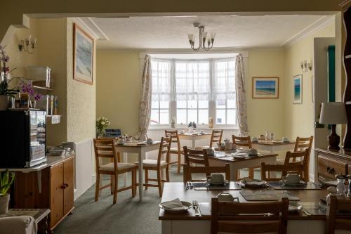 una sala da pranzo con tavoli, sedie e una finestra di Seaspray Guest House a Weymouth