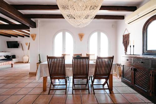 una sala da pranzo con tavolo, sedie e lampadario pendente di Oasis Living Can Nirvana - Best Sea Sunsets a Cala Tarida