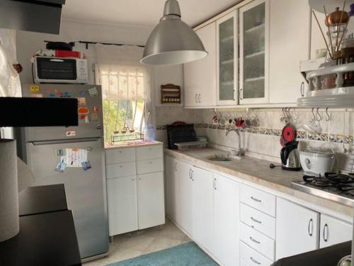 eine Küche mit weißen Schränken und einem Kühlschrank aus Edelstahl in der Unterkunft Cheerful Bodrum Home in Bodrum City