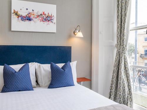 a bedroom with a bed with blue pillows and a window at The Washington in Bristol