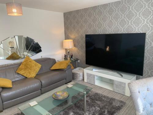 a living room with a couch and a large television at Kensington Luxury Apartment on Gated Development in Leafy edge of Chorley Town Centre in Chorley
