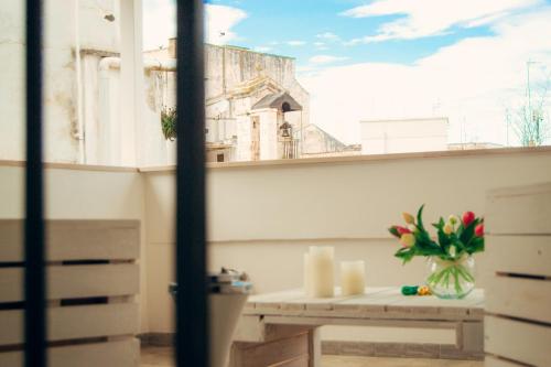 d'un balcon avec une table, des fleurs et une fenêtre. dans l'établissement Meraviglie del Sud, à Castellana Grotte