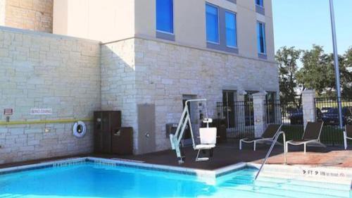 a swimming pool with two chairs and a building at Hyatt Place Austin Airport in Austin