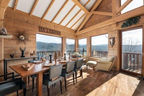 uma sala de jantar com mesa, cadeiras e janelas em Luxueux chalet avec vue sur les pistes et le Hohneck em Le Tholy