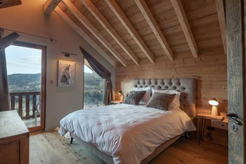 um quarto com uma cama grande e uma janela grande em Luxueux chalet avec vue sur les pistes et le Hohneck em Le Tholy