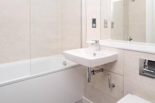 a white bathroom with a sink and a bath tub at Luxury Free Parking Townhouse in Manchester