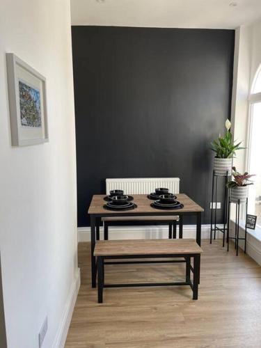 a table and bench in a room with a black wall at Modern 2 bedroom beach house in Cleethorpes