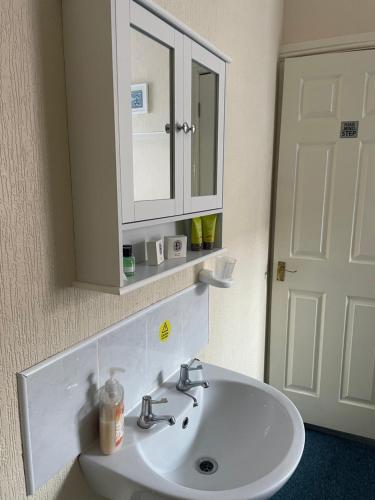 W łazience znajduje się biała umywalka i lustro. w obiekcie Ivydene Guest House w Skegness