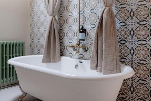 a bathroom with a bath tub with towels on a wall at The Dell of Abernethy - A Woodland hideaway in Nethy Bridge