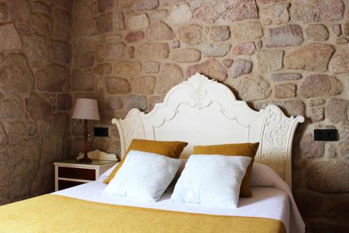a bedroom with a white bed with a stone wall at Casa Valdamor in Meaño