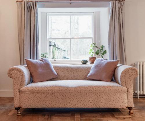 a couch in a living room with a window at The Dell of Abernethy - A Woodland hideaway in Nethy Bridge