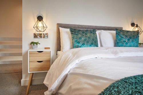 a bedroom with a bed with blue pillows and a night stand at Host & Stay - The Bach in Beadnell