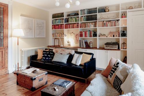 a living room with a black couch and a book shelf at The Dell of Abernethy - A Woodland hideaway in Nethy Bridge