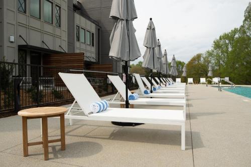 een rij ligstoelen met parasols naast een zwembad bij Hotel Hartness in Greenville