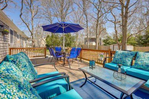 a patio with blue furniture and a table with an umbrella at 2 Mi to Craigville Beach Hyannis Home with Deck in Hyannis