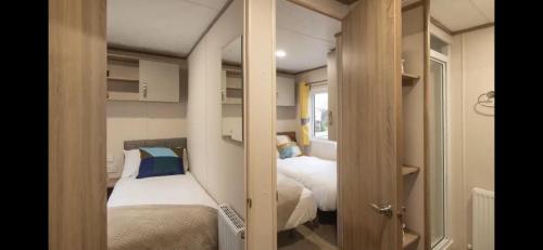 a small room with two beds and a closet at Coopers Beach 3-Bed Caravan Sleeps 8 & Pets Ok in Colchester