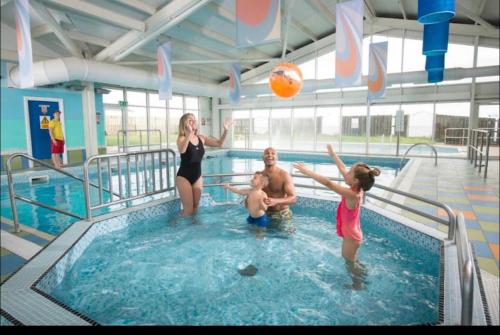 a woman and two children playing with a ball in a swimming pool at Fantastic Family 3-Bed static Caravan cooper bea in Colchester