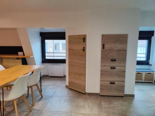 a dining room with wooden cabinets and a table and chairs at Le Green Duplex moderne en hypercentre in Sarreguemines