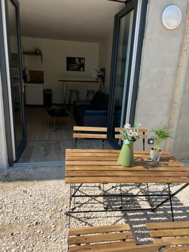 une table en bois avec un vase de fleurs dessus dans l'établissement L’escale de « Nuits », à Nuits-Saint-Georges