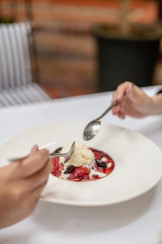 a person holding a plate of food with a spoon at Hotel Boutique Santa Lucia in Cuenca