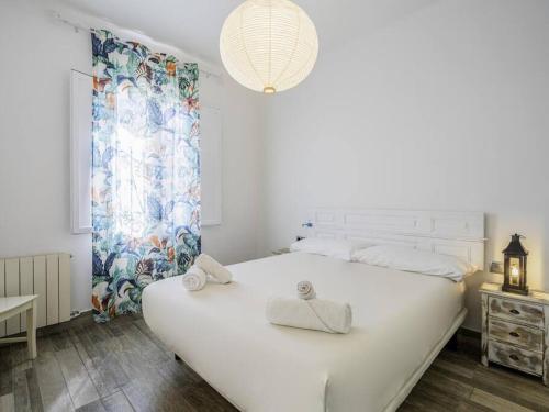 una camera da letto con un grande letto bianco con asciugamani di Fantástica casa reformada en Badalona a Badalona