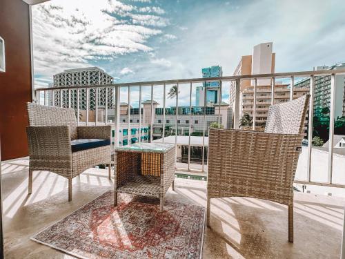 a balcony with chairs and a table and a view of a city at Modern Studio - Heart of Waikiki with Parking! in Honolulu
