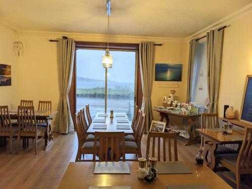 Un comedor con una mesa y un gran ventanal. en Lochaline Hotel, en Lochaline