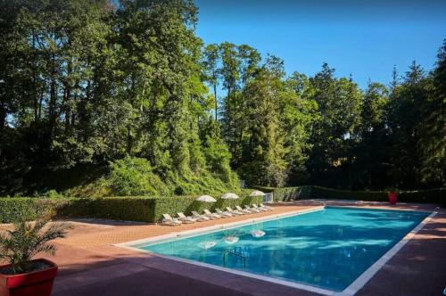 a swimming pool with lawn chairs and trees at MobilHome 3 chambres 6 personnes Piscine Camping Saint Cheron in Saint-Chéron