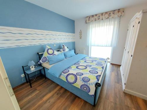 ザスニッツにあるKomfortferienwohnung Leuchtturmのベッドルーム1室(青い壁とウッドフロアのベッド1台付)