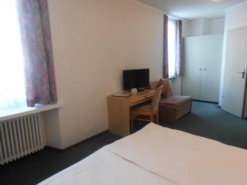a room with a bed and a desk with a television at Hotel Restaurant Escher in Leukerbad