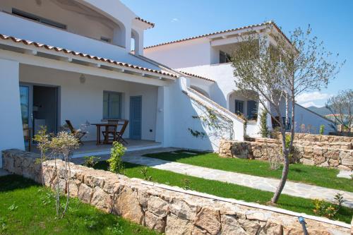 a white house with a stone wall and a yard at ENAJA - Luxury Retreat in Budoni