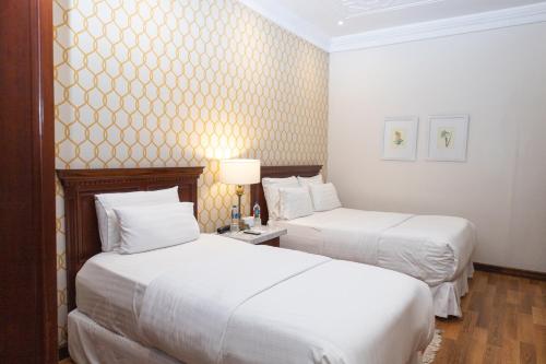 2 camas en una habitación de hotel con sábanas blancas en Hotel Boutique Santa Lucia en Cuenca