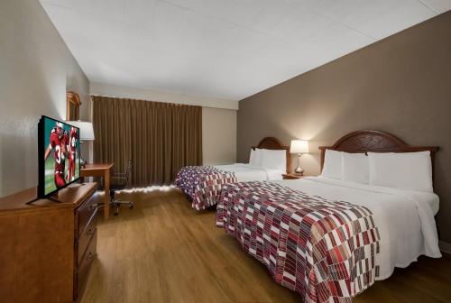 a hotel room with two beds and a flat screen tv at Red Roof Inn and Suites Newark - University in Newark