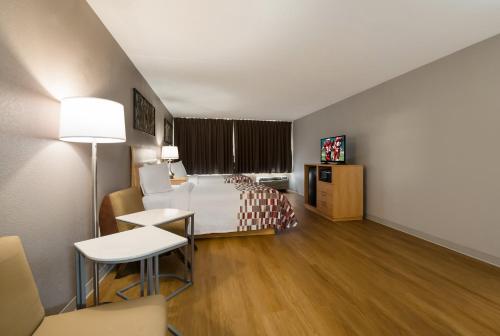 ニューアークにあるRed Roof Inn and Suites Newark - Universityのベッド、テーブル、椅子が備わるホテルルームです。