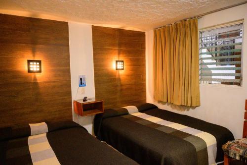 een hotelkamer met 2 bedden en een raam bij Hotel Acuario in Ocotlán