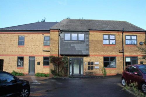 a brick house with a car parked in a parking lot at Marvellous New Build 2 Bed Flat - 1 Ophelia Court in Epsom