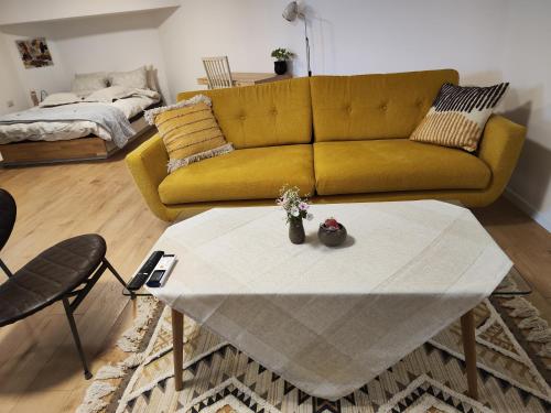 een woonkamer met een gele bank en een tafel bij המקום של מוש in Pardes H̱anna