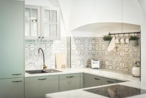 a white kitchen with white cabinets and a sink at Loft w kamienicy in Duszniki Zdrój