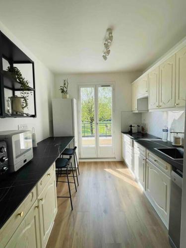 une cuisine avec des armoires blanches et des comptoirs noirs dans l'établissement Marne la Vallée Apartment, à Serris