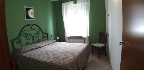 zieloną sypialnię z łóżkiem i oknem w obiekcie Marianna casa vacanza w mieście Azzate
