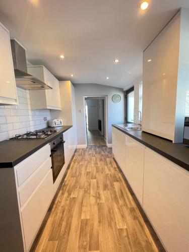 a kitchen with white cabinets and a wooden floor at Edith Haven Tynemouth Fabulous Coastal Holiday Home in Tynemouth