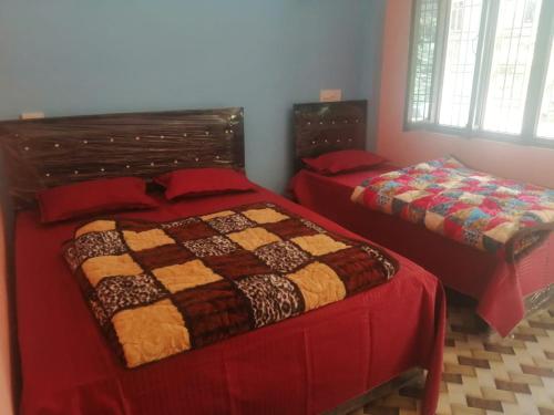 a bedroom with two beds with red sheets at Prince Homestay & Restaurant in Rudraprayāg