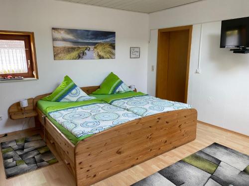1 dormitorio con cama de madera y almohadas verdes en Ingrid Merkle aus Neckarsulm en Karby