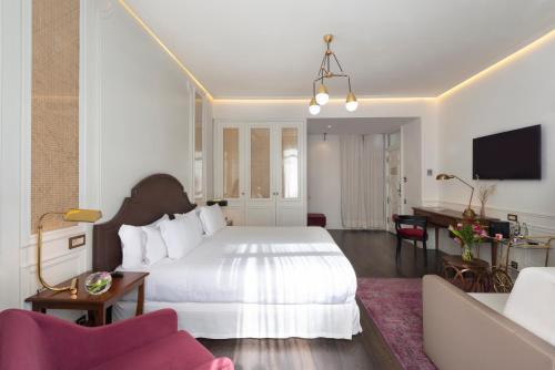 a bedroom with a large white bed and a living room at Boutique Hotel H10 Villa de la Reina in Madrid