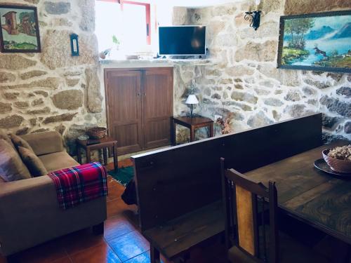 a living room with a table and a stone wall at Casa rural Buxo Ribeira Sacra in Carballedo