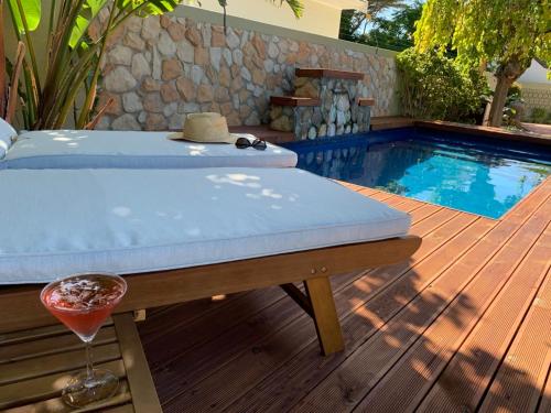 a pool with a bed and a drink on a wooden deck at SOLAR POWERED - Heart of Constantia2 in Cape Town