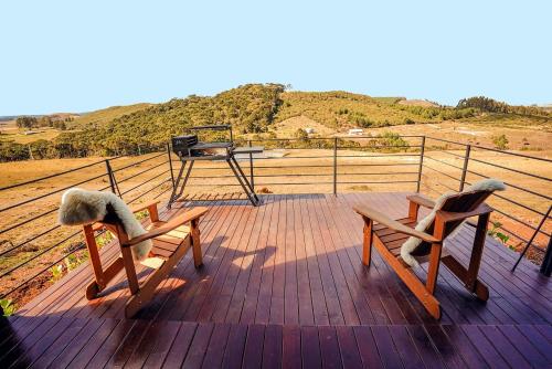 two benches sitting on a deck with a grill at Nordic Cabanas in Cambara do Sul