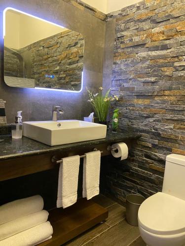 a bathroom with a white sink and a stone wall at Picturesque Ocean View Condo in San Felipe de Puerto Plata