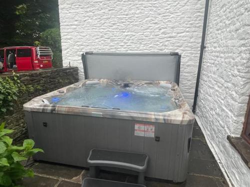 a hot tub sitting next to a white building at Large Historic Farmhouse in Rhondda Valley Perfect for Groups with Hot Tub in Blaencwm