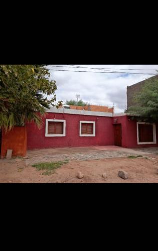 a red building with two windows on the side of it at Posada Chaupihuasi in Villa Unión